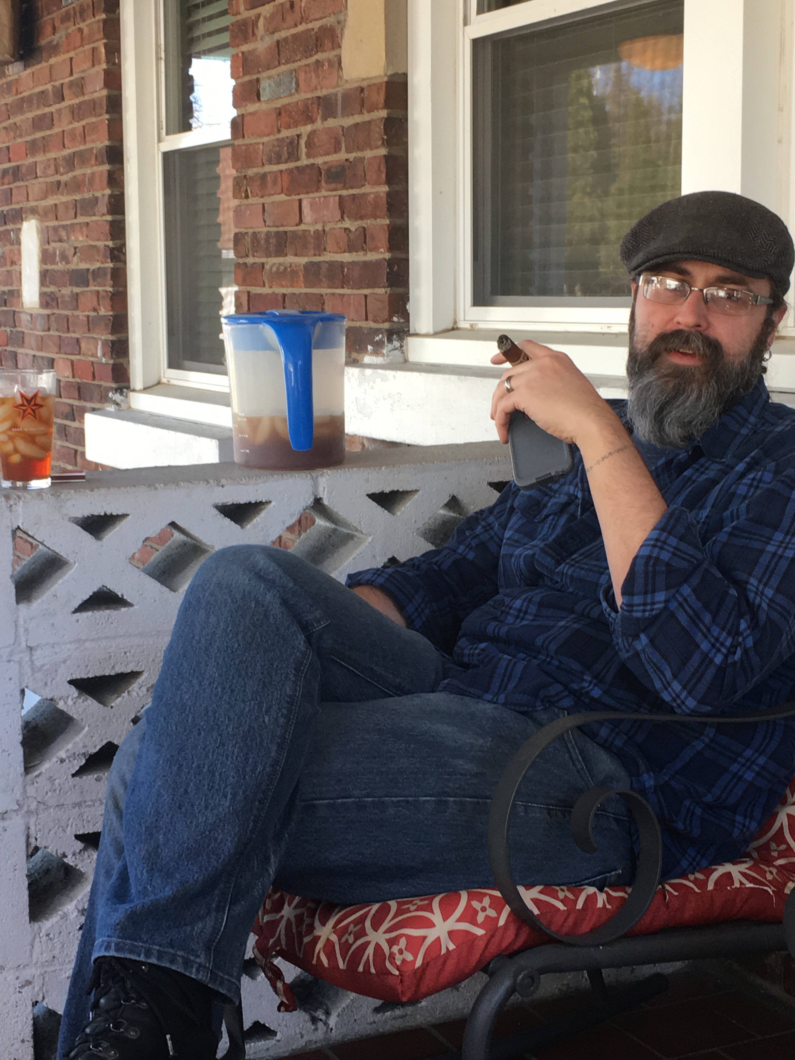 Man on outdoor patio with iced tea and cigar