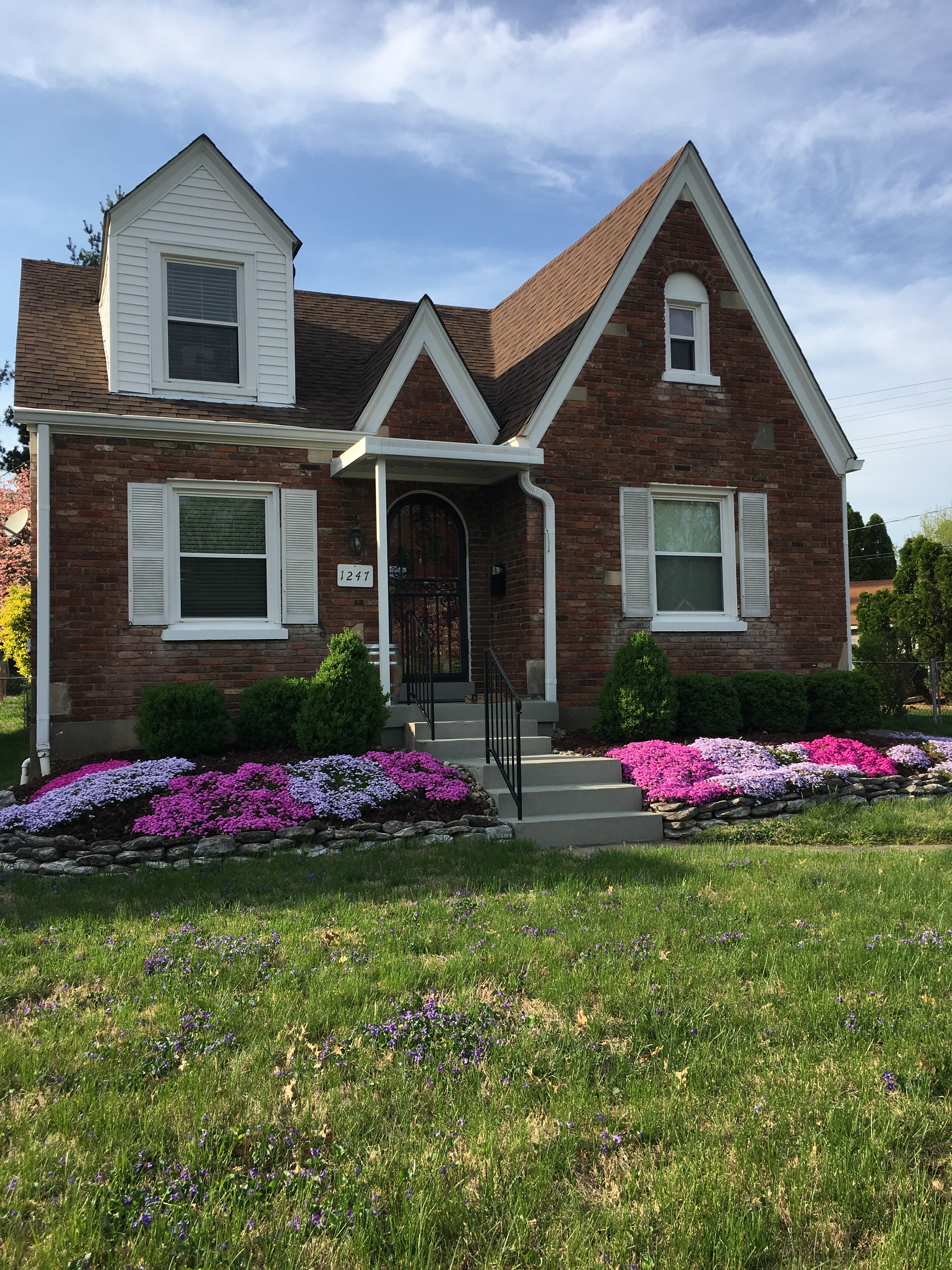Brick home with pink and purple flowers in front